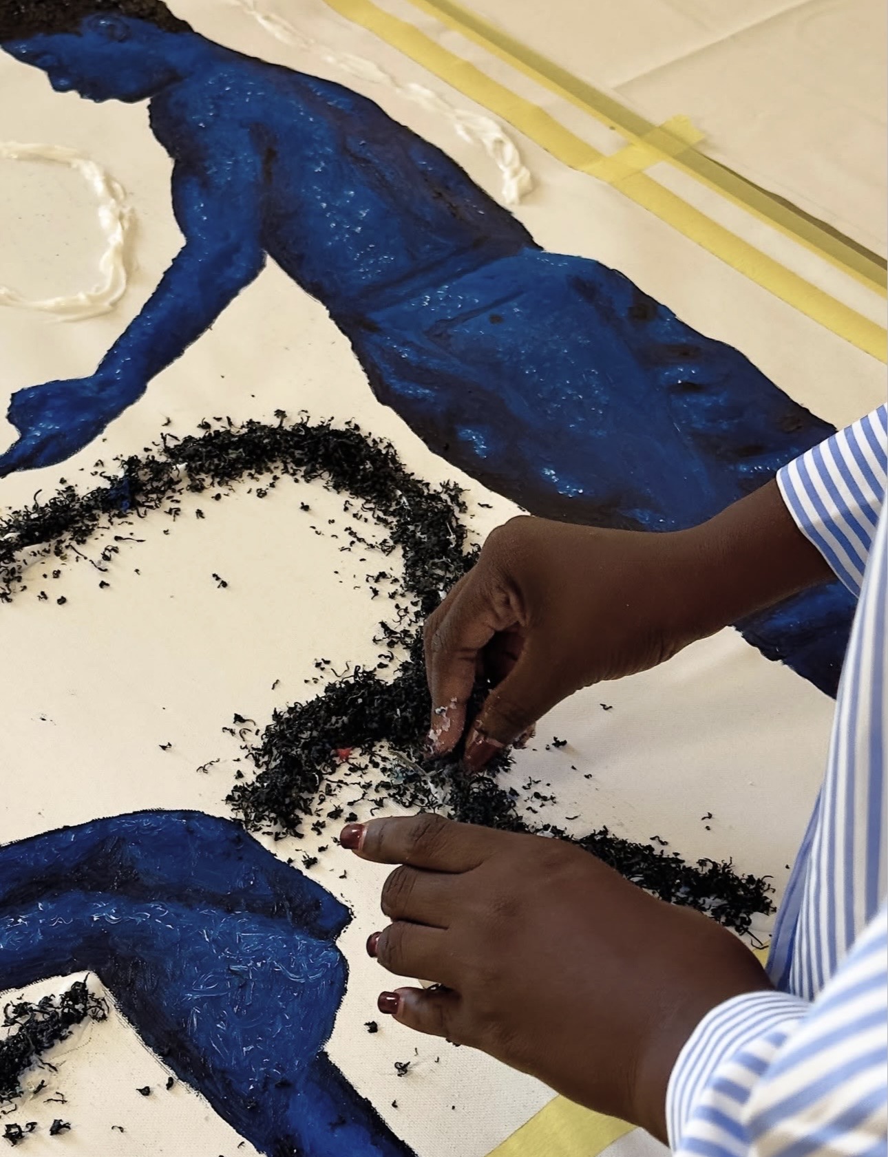 El-ham Tabsoba applying shredded recycled plastic to a painted surface by hand during the Naxos residency