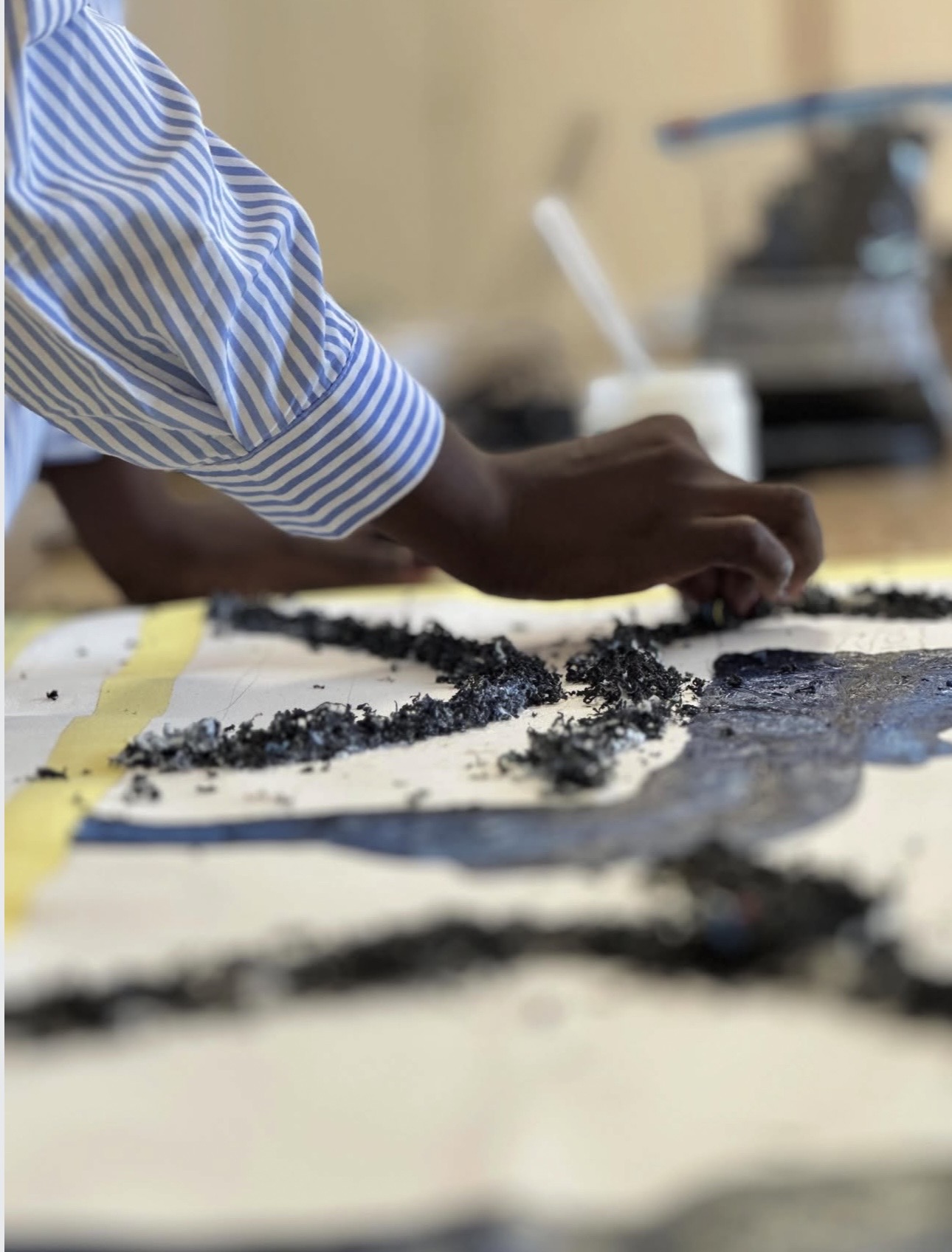 Close view of El-ham Tabsoba integrating shredded recycled plastic into a figurative painting during the Naxos residency