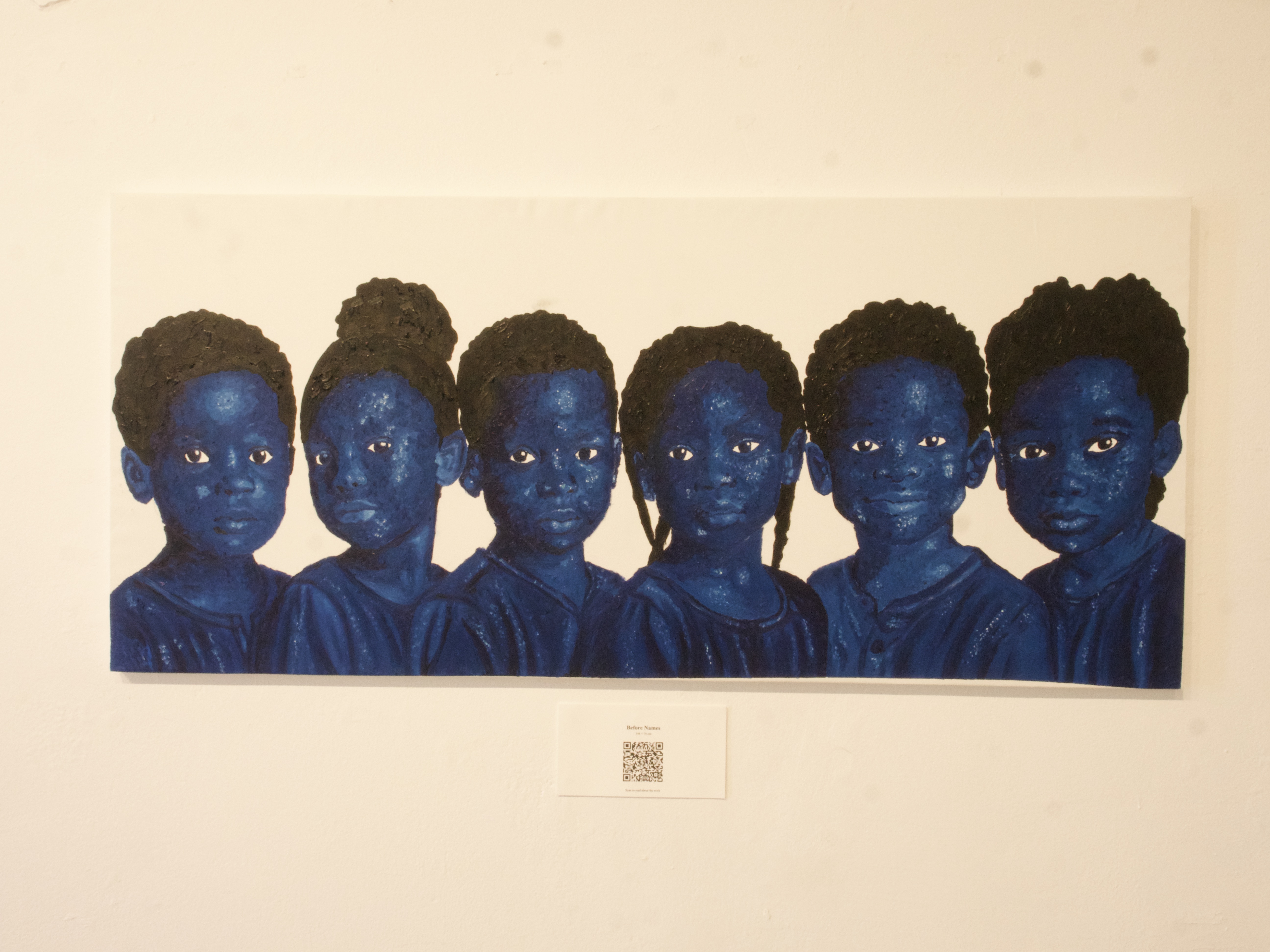 A panoramic painting of six blue figures installed on a white gallery wall in Naxos, Greece