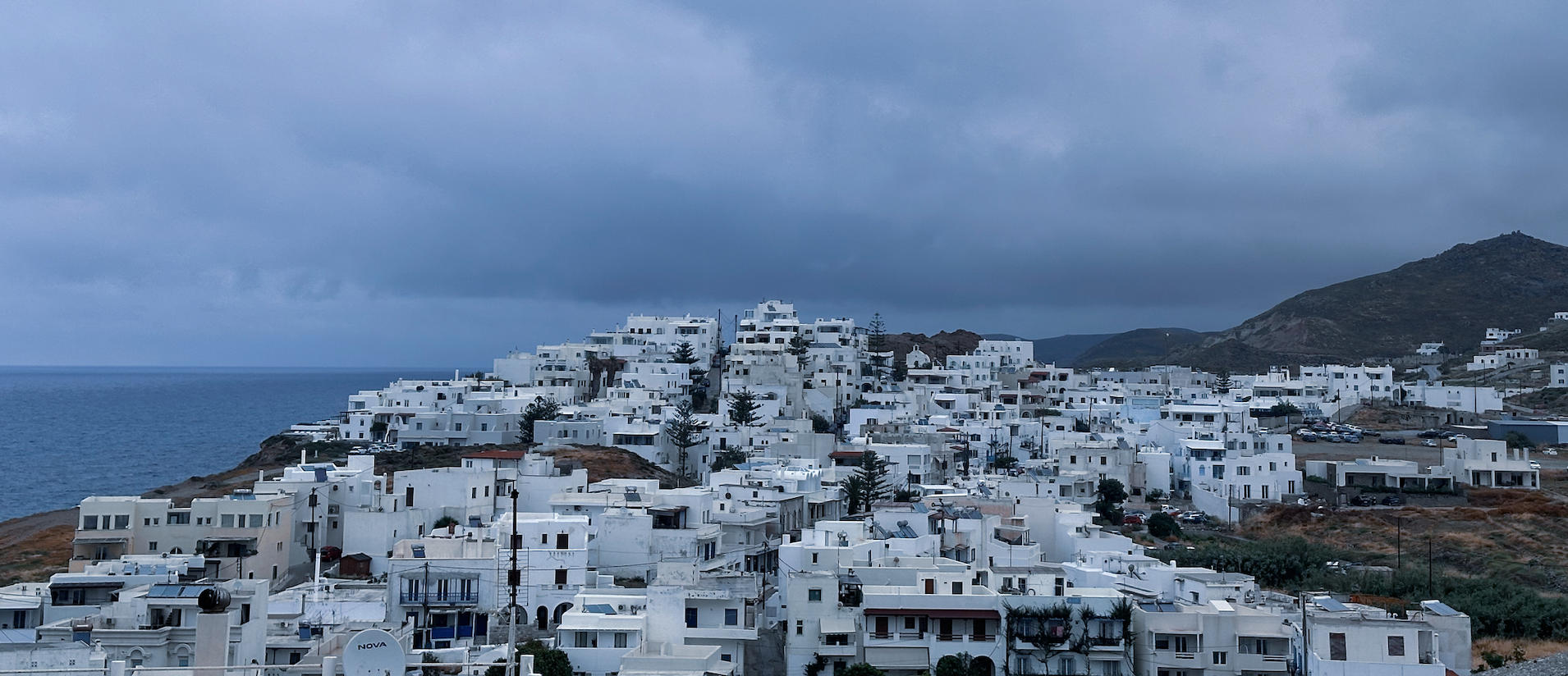 White buildings of Naxos beneath a blue-grey sky beside the Aegean Sea